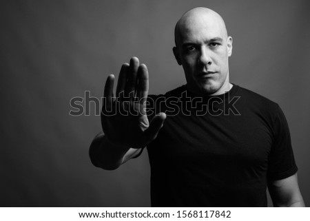 Handsome bald man against gray background in black and white.
