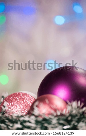 Christmas card with shiny colored toys.  Background with blurred lights garlands, multicolored toys on one side of the picture. Copy space