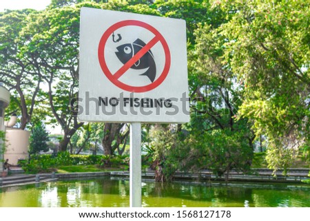 No Fishing signboard in green outdoor park on a hot sunny day