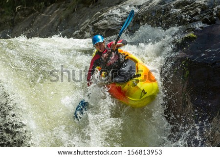 A thrilling white water adventure in Ecuador's extreme rapids, navigating through a waterfall, with kayaks and rafts on the rushing river. Royalty-Free Stock Photo #156813953