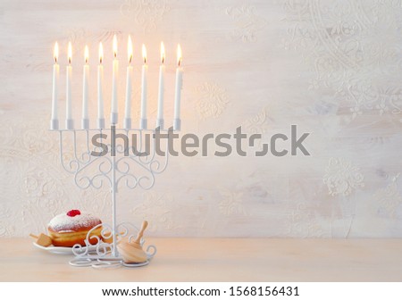 religion image of jewish holiday Hanukkah with menorah (traditional candelabra), spinning top and doughnut over white background