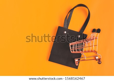 Flatlay template for sale shopping, black Friday, paper packaging, metal shopping cart on yellow background