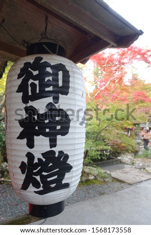 A Japanese Paper Lantern with Colorful Autumn Leaves Background in a Shrine. Japanese Characters on the lantern means "Sacred Lantern".