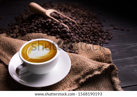 Cup of coffee latte with heart shape and coffee beans on old wooden background Royalty-Free Stock Photo #1568190193