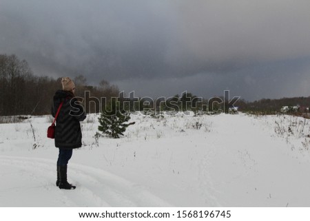  photo of a girl with a camera.she takes pictures of the winter landscape.it's cold outside.in the field lies white snow.a distant forest.