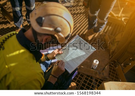 Construction miner supervisor wearing white safety helmet signing working at height working permit on open field job site prior to starting high risk work each shift construction mine site Australia