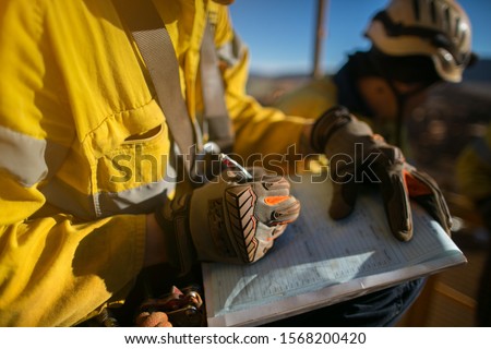 Construction miner supervisor wearing  safety glove signing working at height working permit on open field job site prior to starting high risk work each shift construction mine site Australia
