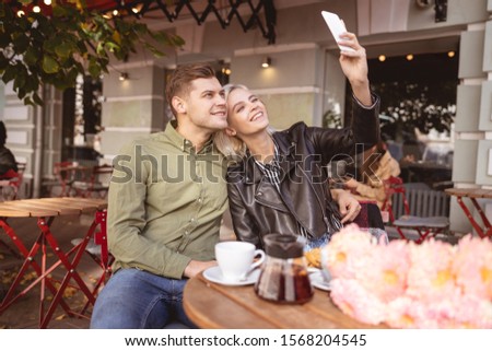 Beautiful young female taking selfie with her cheerful handsome boyfriend