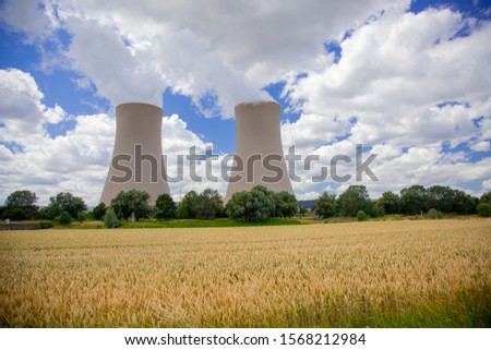 Corn field in front of cooling towers of a nuclear power plant on the Weser river in central Germany. Picture was taken from the Weser Radweg in summer.