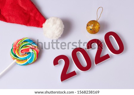 Red numbers 2020 on a white background, blank for a postcard to the designer. Lollipop, cap with pompom