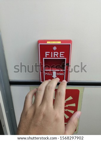 Man hand almost pull down emergency fire alarm. Red fire alarm.