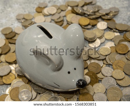 Gray mouse-piggy Bank on a pile of coins . Symbol of the year.