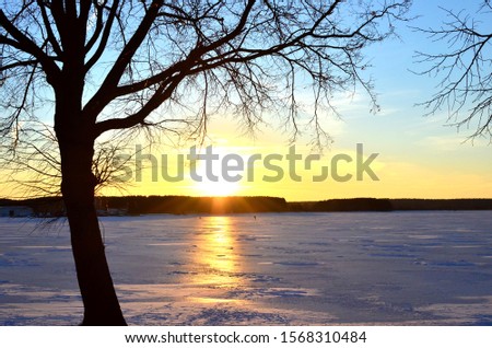 Beautiful winter sunset on a background of a frozen lake. Winter arrives, bodies of water freeze over, People walk on ice of the river. Minsk, Belarus, "Minsk Sea". Funny winter holidays concept image