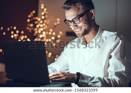 Smiling young guy working during late evening stock photo