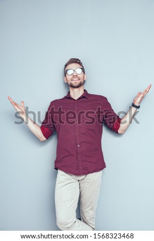 Happy guy wearing glasses and staying against a grey background