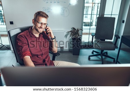 Young man holding mobile phone in office stock photo