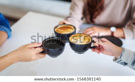 Closeup image of people enjoyed drinking and clinking coffee cups together on the table in cafe