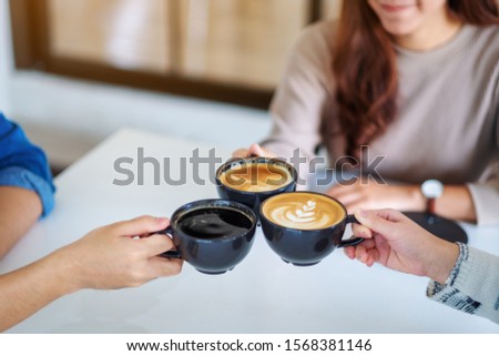 Closeup image of people enjoyed drinking and clinking coffee cups together on the table in cafe