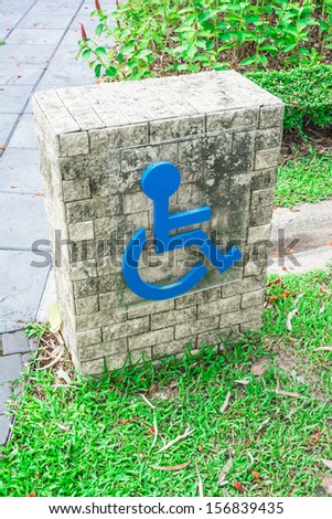 old stone label sign of blue people living with disabilities design on brick block on public nature park