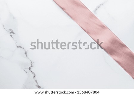 Birthday, wedding and girly branding concept - Beige silk ribbon and bow on marble background, glamour present mockup and fashion gift decoration for luxury beauty brand holiday flatlay design