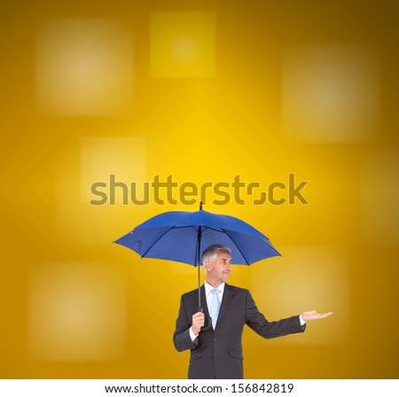 Composite image of mature businessman holding blue umbrella on yellow background