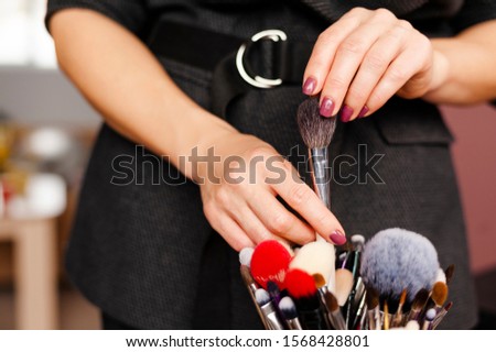 Woman makeup artist select and takes out brush from professional makeup brushes set. Closeup hands