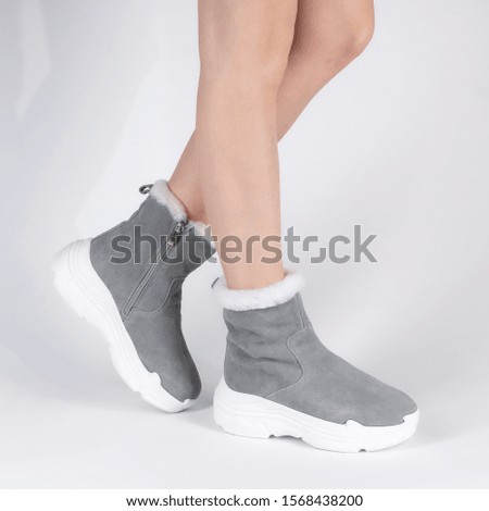 Stylish womens soft warm winter boots with fur inside. Photo on legs of a model on a white background