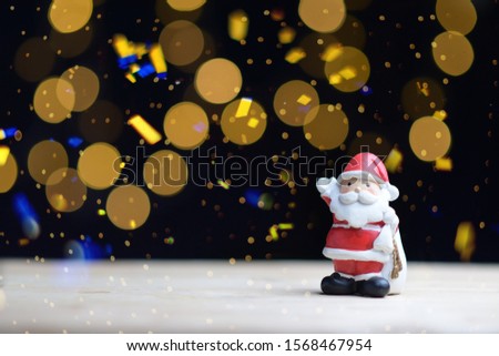 Santa doll on a black background with golden bokeh, happy new year, merry christmas