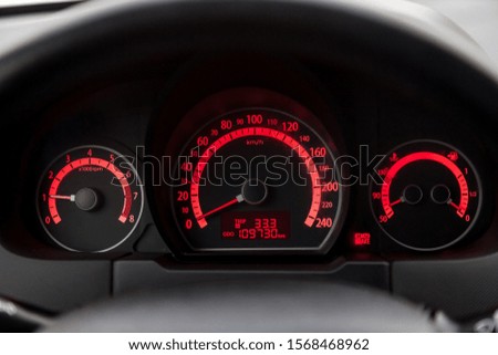 The dashboard of the car is glowing white with orange arrows at night with a speedometer, tachometer and other tools to monitor the condition of the vehicle in classic style