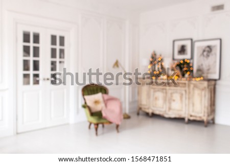 Blurred photo of dresser with Christmas decorations standing on it stands next to chair