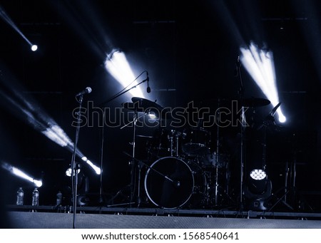 Musical instrumentation on stage before a performance, visible microphones, drums and lights, monochrome image. Royalty-Free Stock Photo #1568540641