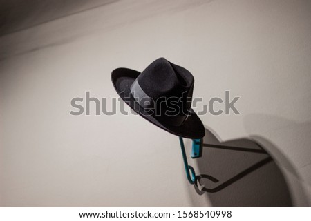 Black traditional men's hat on a hanger.