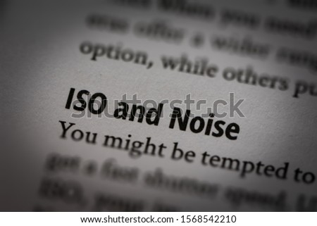 Macro photograph of words "ISO and Noise" in white page of a book about photography with small vignette applied.