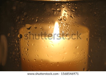 candle light behind glass with water drops