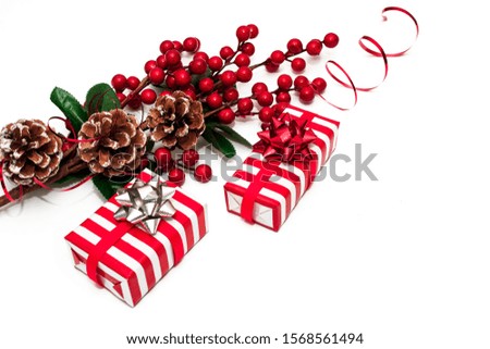 Christmas decor. Christmas card with a branch with red berries and cones, decorated with a red ribbon. Gift boxes in paper with red and white stripes. Flat lay and copy space.