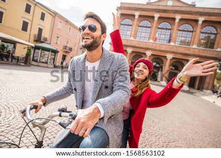 Happy young couple having fun going for a bike ride on a autumn day in the city