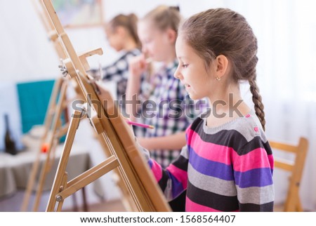 children draw on an easel in art school