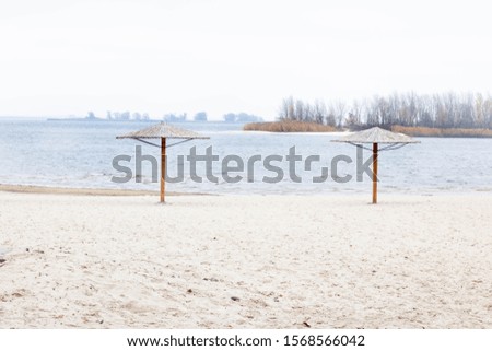 deserted autumn beach with straw umbrellas