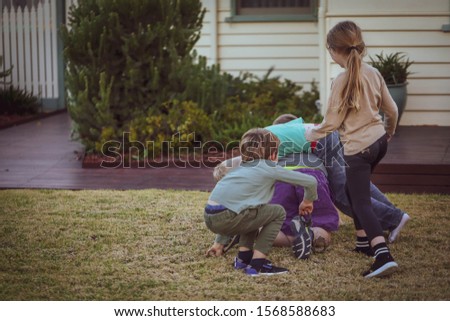 Four children play wrestling on the lawn