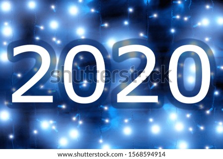glowing 2020 christmas holiday new year blue glow background. Wide view of outdoor festive decoration with 2020 lettering against garland lights. New year 2020 celebration blurred backdrop for design
