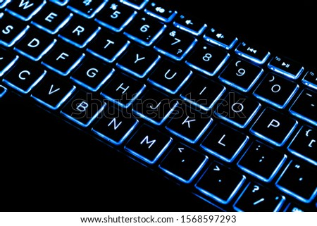 Close up view of a modern laptop computer keyboard keys. Soft lightning in blue tones. Pc computer keyboard close up