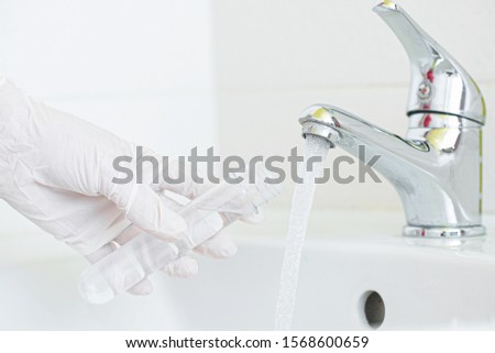 Tap water analysis quality control concept. Hand with a flask and water tap ckose up. Royalty-Free Stock Photo #1568600659