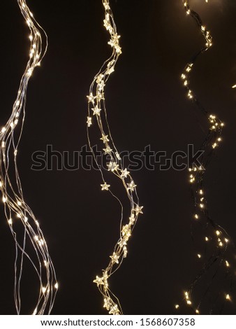 Star and sleeve Christmas lights, fairy lights hanging in a wave form next to each other on dark background.