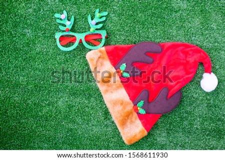 Glasses and christmas hat on green background