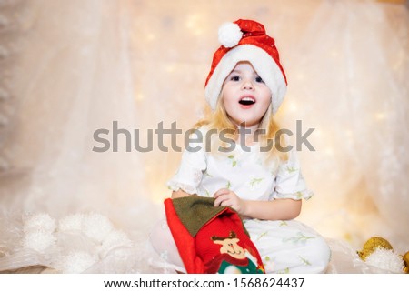 Surprised cute child girl opening a Christmas present. It's Christmas time! Adorable little girl open her stocking gifts on Christmas morning.