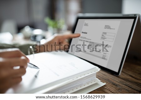 Close-up Of Businessman's Hands Working On Invoice On Laptop At Office Royalty-Free Stock Photo #1568629939
