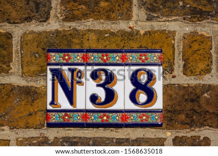 No 38 as a house number on beautiful ceramic tiles on a brick wall