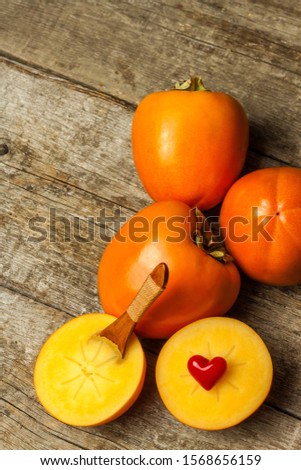 Ripe orange persimmon fruit.Kaki fruit on wooden table.Slices of persimmon.Set of kakis. Fruits of Kaki Persimmon (Diospyros kaki) in japanese autumn