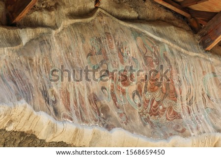 Remnants of painted frescoes-exterior wall of the cliff housing the Mogao caves rock cut into the local sandstone depicting Buddhist imagery spanning the 4th to the 14th century. Dunhuang-Gansu-China.