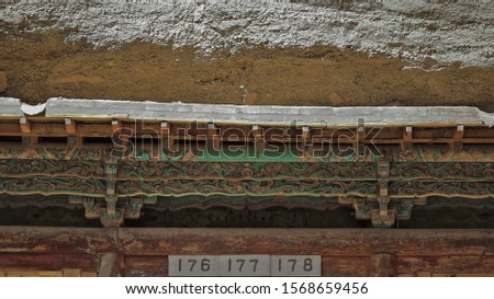 Carved wooden door lintel over caves 176-7-8 polychrome in green-orange-blue. Mogao Caves S.area of 492 caves and cell temples-Buddhist art from centuries 4th to 14th. Dunhuang-Gansu province-China.